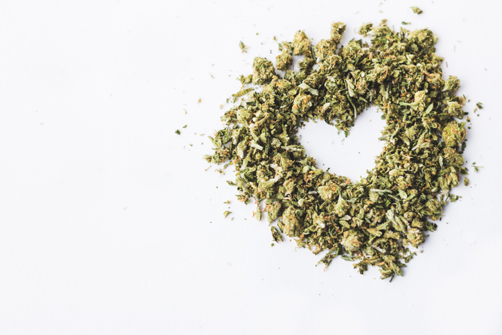 Heart made of crushed up marijuana herb isolated on white background.